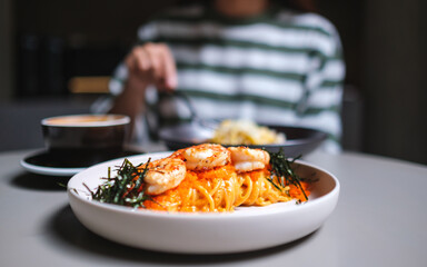 Closeup image of a woman eating spaghetti on dining table