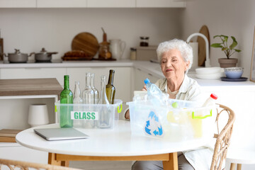Senior woman with containers of garbage writing on notebook in kitchen. Waste sorting concept