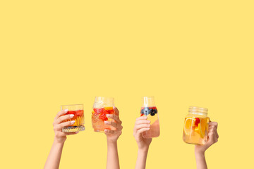 Many hands with infused water on yellow background