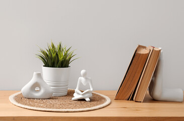 Human figure, books, houseplant and vase on chest of drawers in room. Closeup