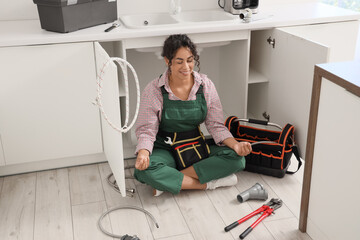 Female African-American plumber meditating in kitchen