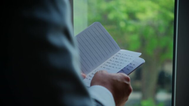 Groom read his vows to bride at wedding day. Closeup shot male hands holding book 