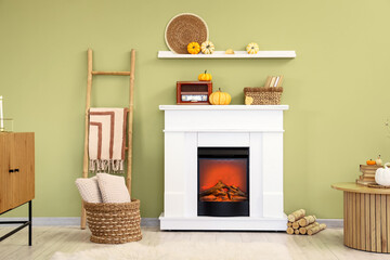 Interior of stylish room with table, vintage radio receiver and pumpkins on modern fireplace near...