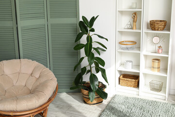 Interior of stylish room with shelving units, armchair, folding screen and houseplants