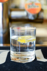 A glass of sparkling water with a slice of lemon is ready for someone to drink