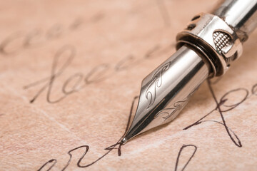 Old paper sheet with letters and nib pen, closeup