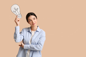 Thoughtful female inventor with paper light bulb on beige background