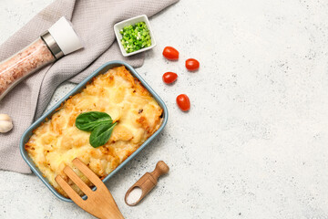 Baking dish with tasty pasta, spinach leaves, tomatoes, cut green onion and sea salt on light...