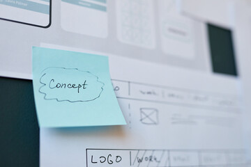 Closeup showing blue sticky note with handwritten word Concept attached to printed website...