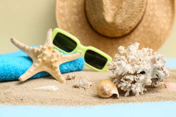 Composition with seashells, starfish, sunglasses, towel and sand on color background