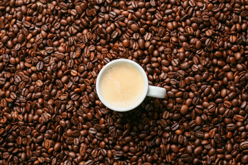 Cup of aromatic coffee on roasted beans