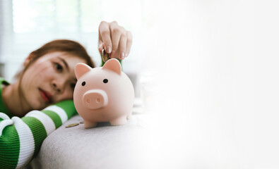 Money saving concept. Close up shot of woman putting coins in piggy bank. Symbol of financial...