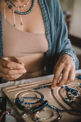 Close up of hands woman jewelry designer. She is sitting at a workspace with tools on it and is creating jewelry by stringing beads on fishing line. The process of creating jewelry. Small business. 