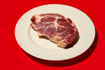 Plate with fresh raw steak on red background, closeup
