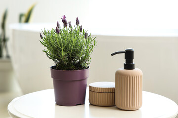 Pot with lavender flowers and cosmetic products on coffee table in bathroom, closeup