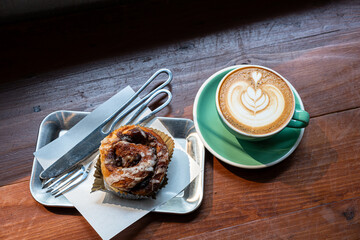 Hot coffee latte with latte art milk foam in cup mug and Homemade Cinnamon Rolls on wood desk on...