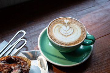 Hot coffee latte with latte art milk foam in cup mug and Homemade Cinnamon Rolls on wood desk on top view. As breakfast In a coffee shop at the cafe,during business work.