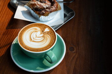 Hot coffee latte with latte art milk foam in cup mug and Homemade Cinnamon Rolls on wood desk on top view. As breakfast In a coffee shop at the cafe,during business work.
