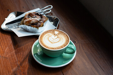 Hot coffee latte with latte art milk foam in cup mug and Homemade Cinnamon Rolls on wood desk on...