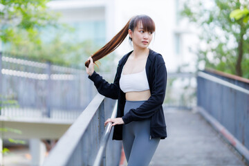 Portrait of beautiful asian Young woman in Black robe sportswear working out outside. training on public equipment in outdoor at park. concept Exercise Healthy lifestyle.