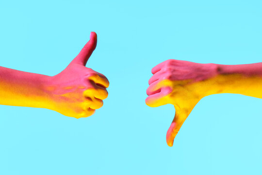 Toned female hands showing thumbs on blue background