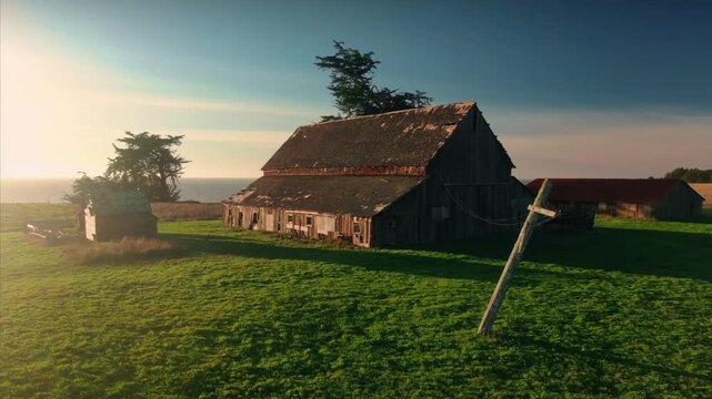 Aerial view of a barn and outbuildings on a farm in  Mendocino, California, USA. The buildings are surrounded by green grass and trees.