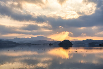 夕陽に照らされた湖面と静かな山々