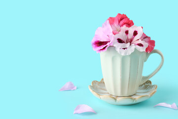 Cup with different beautiful edible flowers and petals on blue background