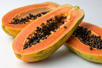 Fresh ripe papaya cut in half revealing bright orange flesh filled with small black seeds in cavity center.