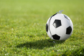 Fototapeta premium Soccer ball and whistle on green stadium grass