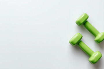 Pair of green dumbbells resting on clean white surface for fitness and exercise