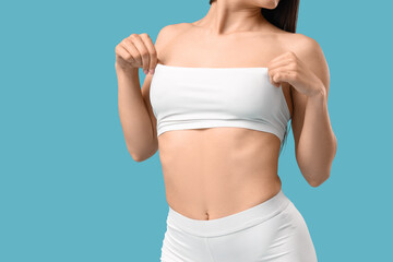 Pretty young woman in stylish white underwear on blue background