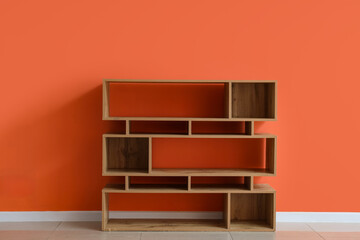 Empty wooden bookshelf near orange wall