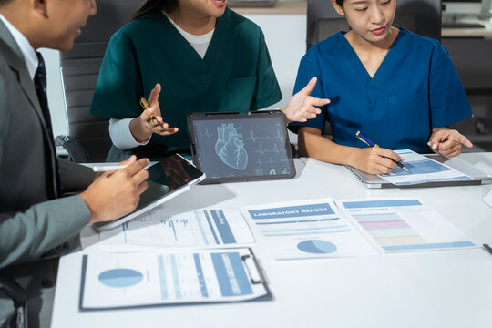 Hospital administrators and physicians sit at a conference table, analyze medical reports, and work as a team to manage healthcare, integrate medical technology, and process clinical decisions
