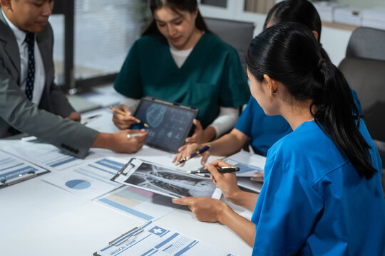 Hospital administrators and physicians sit at a conference table, analyze medical reports, and work as a team to manage healthcare, integrate medical technology, and process clinical decisions