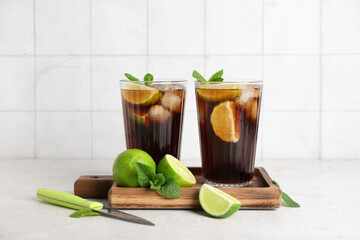 Glasses of cold Cuba Libre cocktail with mint and limes on white table
