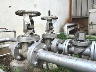 A row of large industrial gate valves and flanged pipes stands in an outdoor setting, showcasing a...