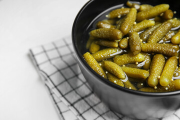 Bowl with tasty pickled cucumbers on white background, closeup