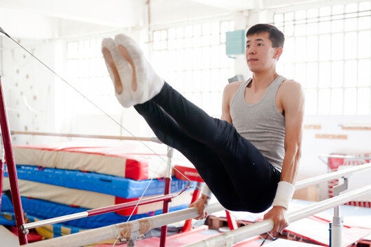 Focused gymnast practicing on parallel bars in gym