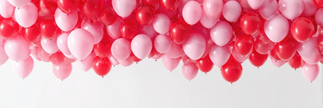 Pink and red balloons cluster against white backdrop