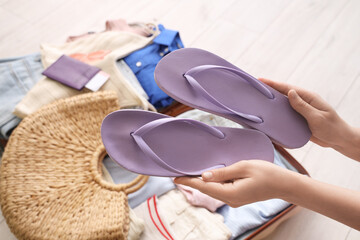 Young woman putting stylish flip-flops in suitcase, closeup