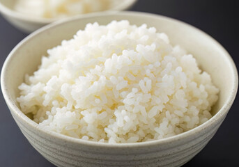 A close-up shot of freshly cooked Japanese white rice, fluffy and perfectly steamed, served in a traditional ceramic bowl, a staple of Asian cuisine.