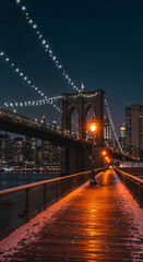 Obraz premium Snowy Brooklyn Bridge walkway with lights at night