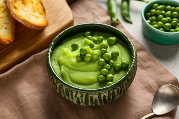 Bowl with mashed green peas and bread slices on grey background, closeup