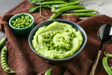 Bowl with mashed green peas on grunge background, closeup