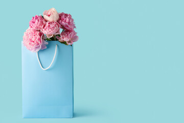 Shopping bag with beautiful pink peony flowers on blue background