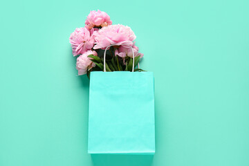 Shopping bag with beautiful pink peony flowers on turquoise background