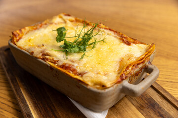 Lasagna served in a ceramic bowl on a wooden board