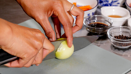 A Hispanic woman slices an onion with precision, evoking culinary rituals of Dia de los Muertos and...
