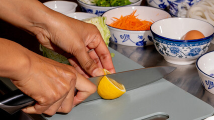 Two hands deftly slicing lemon, evoking spring's zest during Qingming Festival, Asian culinary ritual, vibrant kitchen symphony